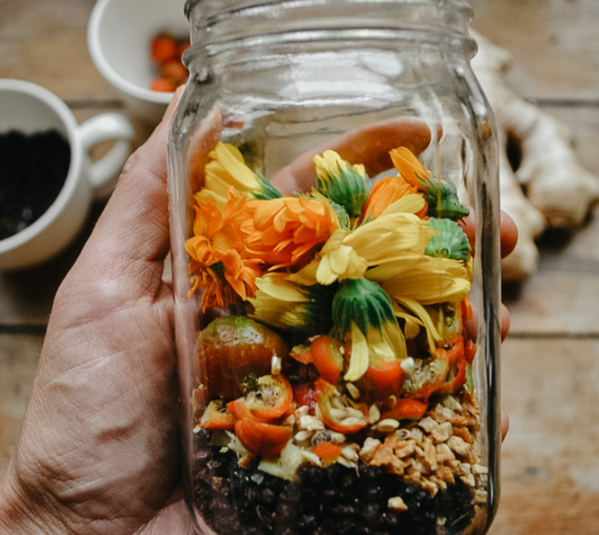 A person holding a clear jar filled with dried herbs.