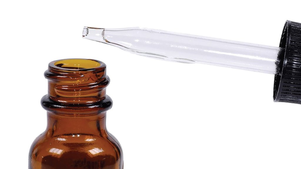 A close up of a tincture bottle with it's pipette dropping liquid into it.