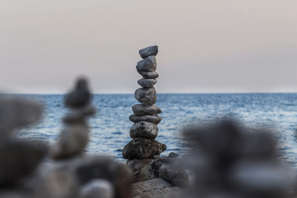 A tall stack of small stones with the ocean in the background.