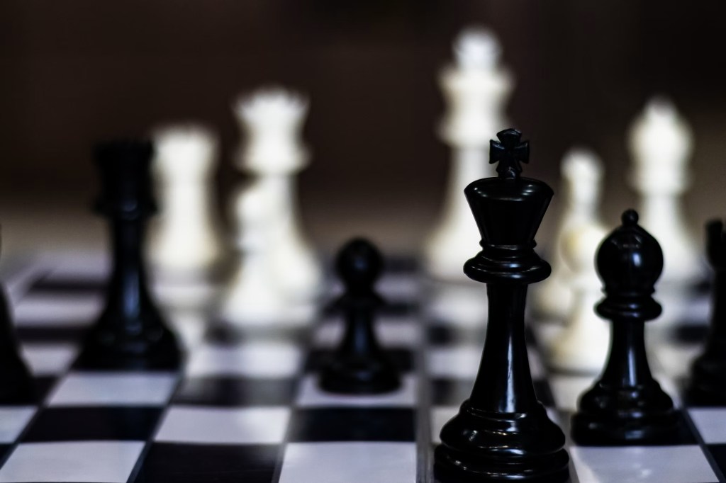 Close up of chess pieces on chess board with a black backdrop.