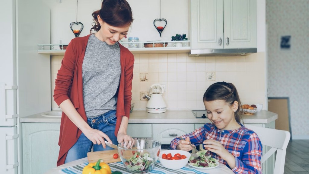 A woman and child fixing food at a kitchen table.