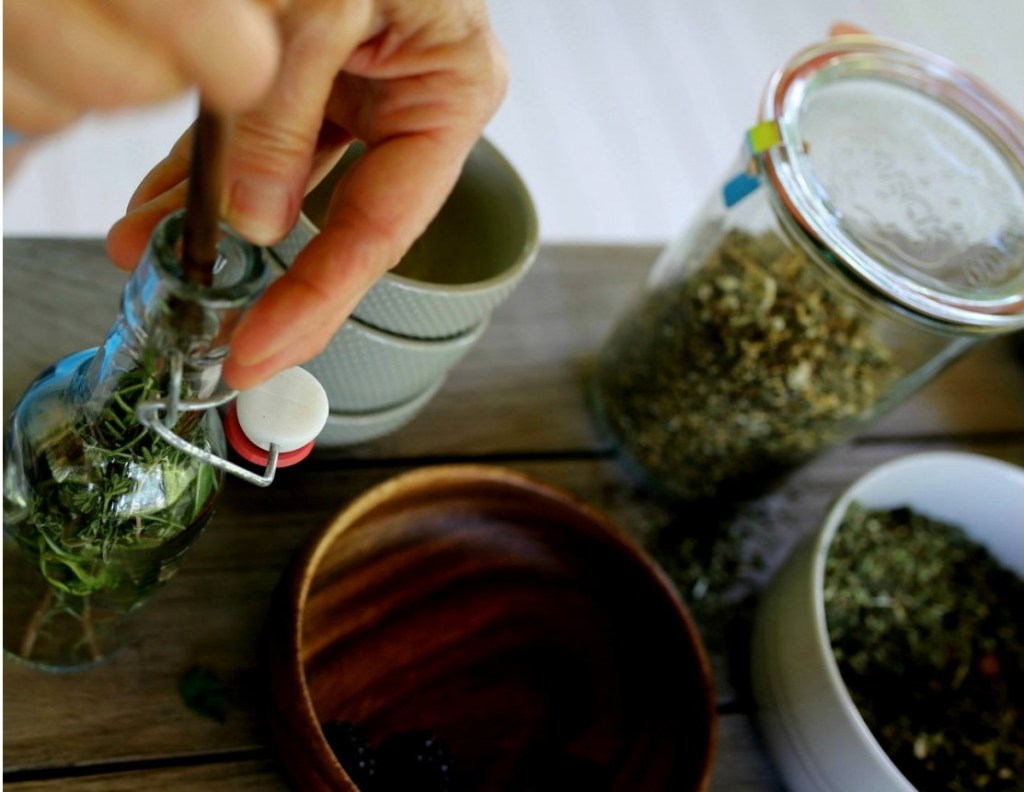 Close up of herbalist working at a table with herbs.