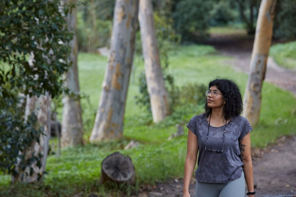 Woman walking a nature trail looking at trees.