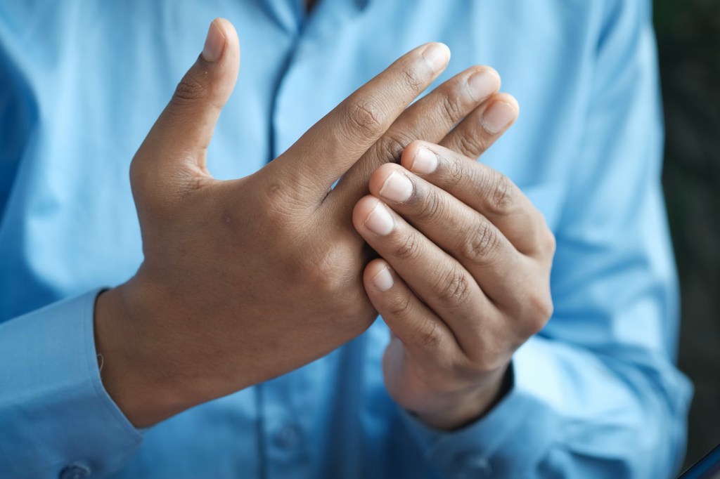 A close up of a person wearing a blue shirt with their hands held in front of them.