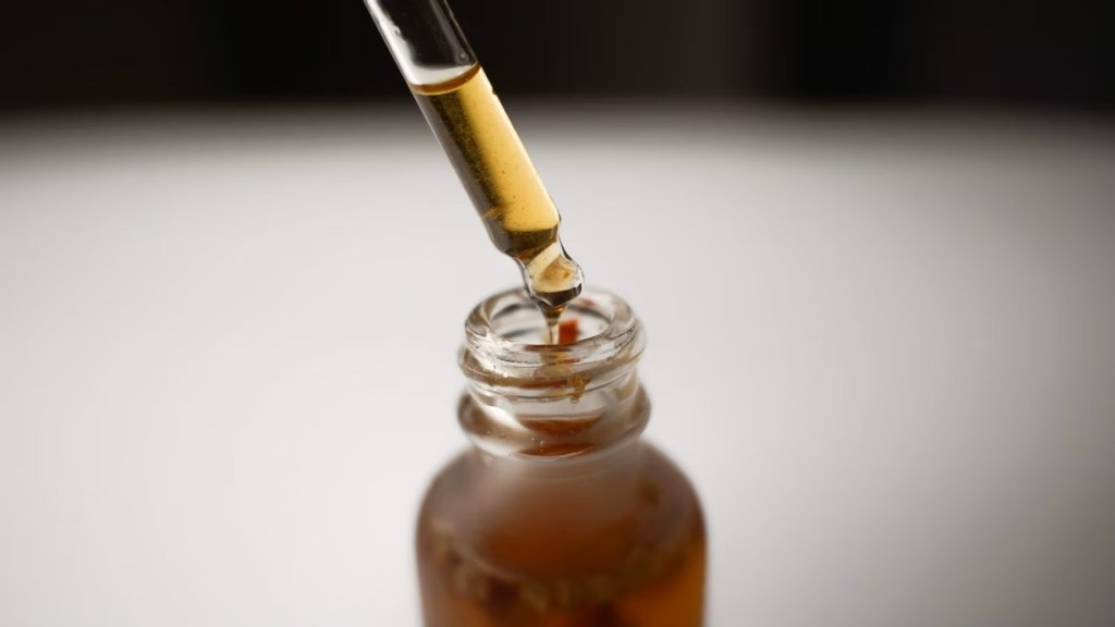 Close up image of a tincture bottle with liquid as the pipette drops liquid in.