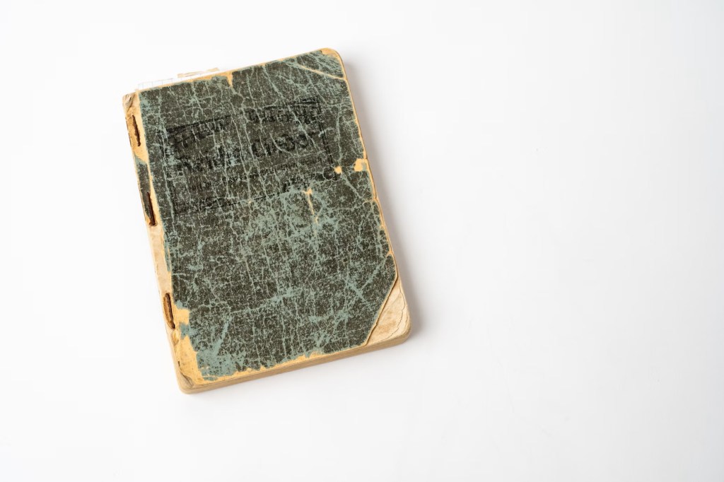 An old book on a white table with a scuffed cover.

