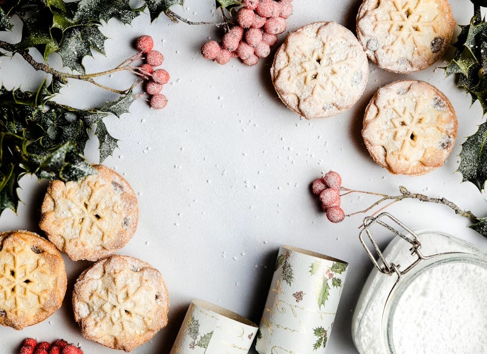 holiday cookies on a white table with holly sprigs