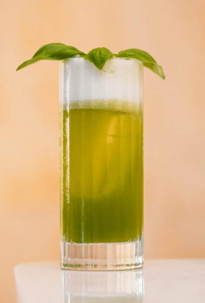 A tall glass of green iced tea with herb springs garnish. 